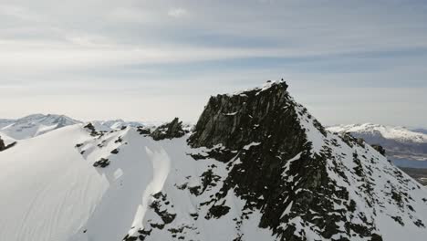 Person-climbing-rocky-mountains-in-Norway,-aerial-panoramic-view