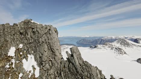 Person-climbing-extremely-dangerous-rocky-mountain-in-Norway,-aerial-view