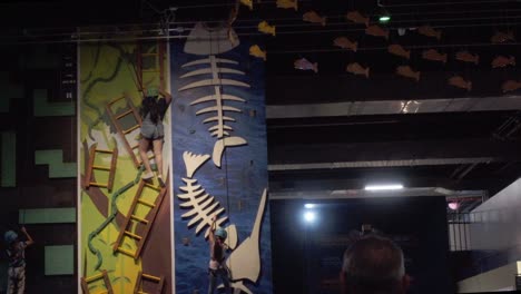 Two-girls-climbing-wall-inside-aquarium