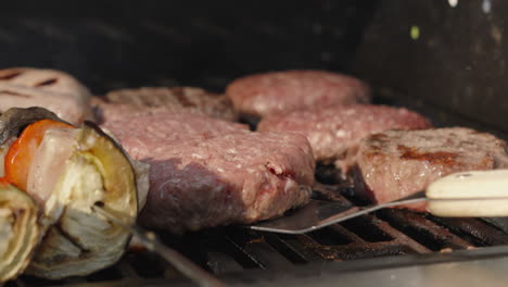 Chef-Flipping-and-Cooking-Beef-Hamburgers-on-Smokey-Hot-BBQ-with-Shish-Kebabs-and-Sausages