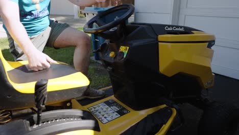 A-person-starting-up-a-riding-lawnmower