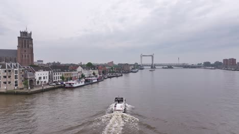 Motorboat-Sailing-Near-Historic-Riverfront-Town-Of-Dordrecht-In-South-Holland,-Western-Netherlands