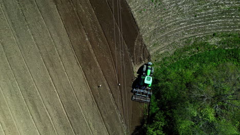 Green-tractor-plowing-arid,-aerial-top-down-view