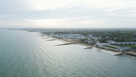 Aerial-pullback-of-scenic-coastline-along-idyllic-Dennis-Port,-Massachusetts-with-stunning-skyline