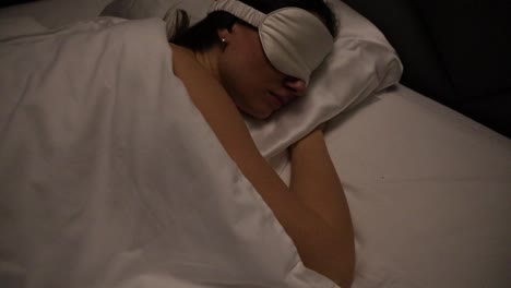 Side-view-of-an-attractive-young-Caucasian-woman-peacefully-sleeping-with-the-sleeping-mask-at-night-alone