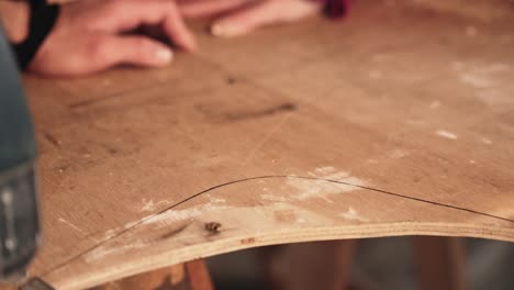 Cut-plywood-while-hands-of-person-holding-it-down,-close-up