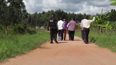 Schwarze-Afrikanische-Polizisten-Gehen-Mit-Einer-Gruppe-Schwarzer-Ureinwohner-Auf-Einem-Abgelegenen-Kleinen-Offroad-Pfad-Spazieren-Und-überprüfen-Den-Tatort,-Korrumpiertes-Afrika-Konzept