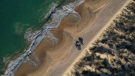 Aerial-top-down-circling-shot-of-two-4x4-vehicles-parking-on-sandy-beach-of-Preston