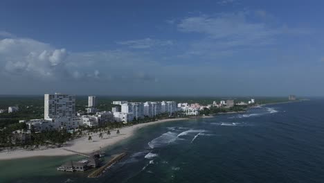 Aerial-pullback-above-Playa-Hemingway-as-waves-crash-over-reef-under-hotels