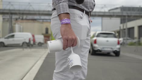 Man-crossing-street-with-empty-re-usable-plastic-wine-glasses-for-a-refill-at-an-event