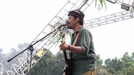 Indonesian-Artist-Singing-While-Playing-Guitar-On-Stage-In-Live-Outdoor-Concert