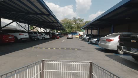 POV-of-shopper-pushing-cart-through-parking-lot-of-large-grocery-store