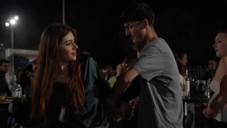 Slow-motion-shot-of-a-young-couple-dancing-and-twirling-at-a-party-at-night