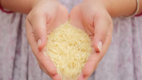 Slow-motion-shot-of-handful-of-grains-of-rice-falling-from-indian-woman