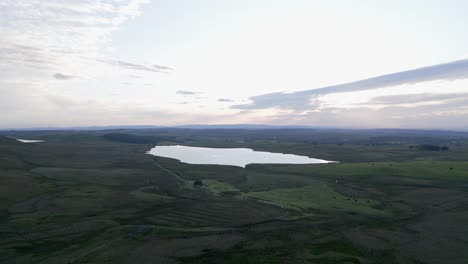 Aerial-approaches-loch-and-lone-spinning-wind-turbine-on-hazy-morning