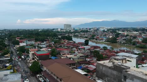 Eine-Drohne-Nimmt-Eine-Luftaufnahme-Von-Davao-City-Auf-Und-Präsentiert-Die-Lebendige-Stadtlandschaft-Mit-Ihren-Niedrigen-Und-Hohen-Gebäuden,-Einem-Fluss-In-Der-Mitte-Und-üppigem-Grün