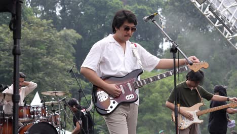 Guitarrista-Indonesio-Afinando-Su-Guitarra-Eléctrica-En-El-Escenario-Con-Una-Banda-De-Música-Antes-Del-Espectáculo-En-Vivo-Al-Aire-Libre