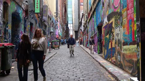 Tourists-visiting-Hosier-Lane-in-Melbourne-city,-a-renowned-cobblestone-laneway-showcasing-a-vibrant-array-of-art-murals-and-graffiti-adorning-the-exterior-walls-of-buildings