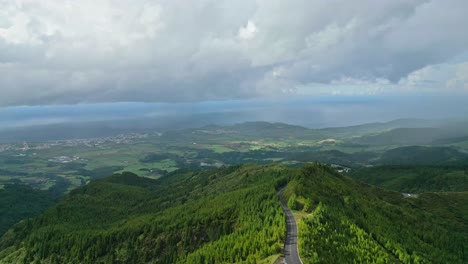 Wide-forward-aerial-of-country-road-on-green-mountain-in-the-Azores