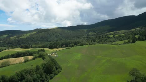 Lagoa-do-fogo-with-green-fields,-hills,-and-ocean-in-the-background,-aerial-view