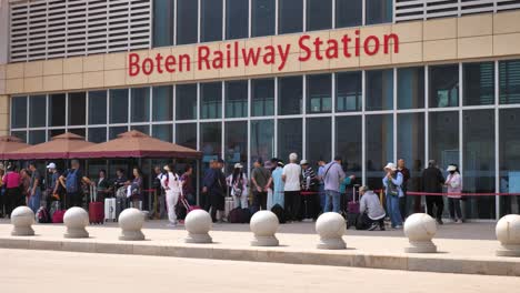 People-waiting-outside-Boten-Railway-Station,-traveling-through-Laos-into-China-on-a-sunny-day
