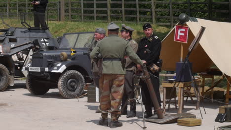 Soldados-Del-Ejército-Alemán-De-La-Segunda-Guerra-Mundial-Con-Uniformes-Que-Presentan-Una-Tienda-De-Campaña,-Un-Mortero-Y-Diversos-Equipos-Con-Un-Vehículo-Militar-Antiguo-Y-Alambre-De-Púas.