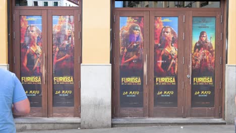 Ein-Kinobesucher-Betritt-Ein-Kino,-Das-Mit-Werbeplakaten-Für-Den-Film-„Furiosa:-A-Mad-Max-Saga“-Geschmückt-Ist,-Einen-Postapokalyptischen-Actionfilm-Unter-Der-Regie-Und-Produktion-Von-George-Miller