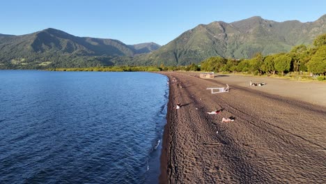 Tourists-sunbathing-on-the-black-sandy-shores-of-lake-villarrica-in-Chile
