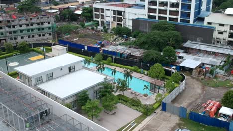 Tomas-Aéreas-De-Drones-De-Una-Urbanización-Moderna-En-La-Ciudad-De-Davao-Con-Una-Piscina-En-El-Centro-Del-Club-Y-El-Edificio-Vecino.