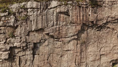 Woman-climbing-rock-wall-in-Norway,-aerial-view