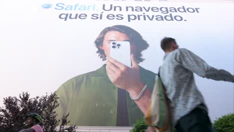 Captured-from-a-low-angle,-pedestrians-walk-past-a-prominent-Apple-billboard-highlighting-the-privacy-features-of-the-Safari-web-browser,-from-the-American-multinational-technology-giant