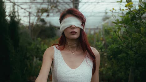 cinematic-slow-footage-of-young-woman-in-a-white-dress-and-blindfolded-walks-with-a-stretched-arm