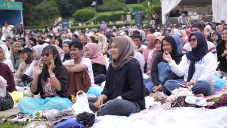 Indonesische-Jugendliche-Sitzen-Auf-Dem-Boden-Und-Schauen-Sich-Ein-Open-Air-Konzert-An