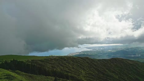 Las-Nubes-Se-Ciernen-Sobre-Las-Exuberantes-Colinas-Verdes-De-La-Laguna-Do-Fogo-Con-Una-Vista-Lejana-Del-Océano