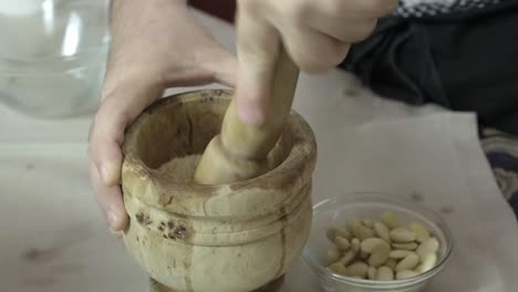 Close-shot-of-a-mortar-grinding-nuts,-chef's-hand-in-the-kitchen