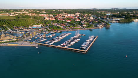 High-angle-circle-aerial-over-shoreline-of-Peschiera-del-Garda-lake,-Verona,-Italy-4K-stock-video