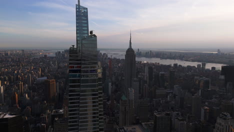 Aerial-view-rising-around-the-One-Vanderbilt-building,-hazy-sunset-in-New-York