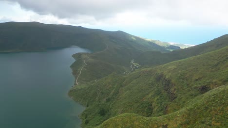 Lush-green-hills-surround-a-serene-lake-under-a-cloudy-sky-in-Lagoa-do-Fogo,-Azores