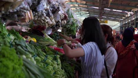 Las-Mujeres-Navegan-Entre-Verduras-Verdes-En-El-Mercado-De-Alimentos-De-Indonesia,-Slomo