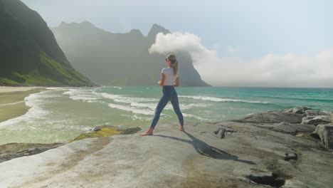 Yoga-warrior-pose-done-by-attractive-woman-on-coastline-of-Norway