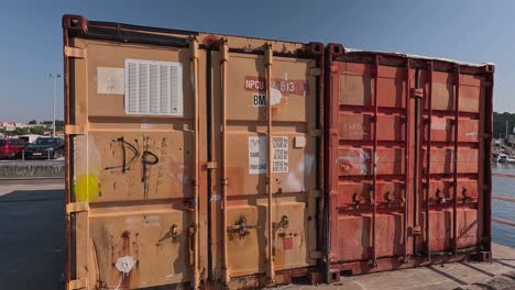 Alte-Rostige-Und-Verlassene-Schiffscontainer,-Die-In-Lagerräume-Für-Fischerwerkzeuge-Und--utensilien-Im-Hafen-Umgewandelt-Wurden,-Beschreibende-Nahaufnahme,-Neigung