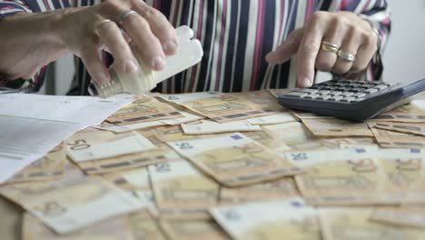 Las-Manos-De-Una-Anciana-Calculan-Ideas-Y-Dinero,-Factura-En-Euros-En-El-Escritorio-De-La-Oficina-En-Casa