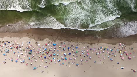 Vista-Aérea-De-Pájaro-Sobre-La-Playa-De-Maitencillo-Con-Bañistas-Y-Coloridas-Sombrillas,-Olas-Rompiendo