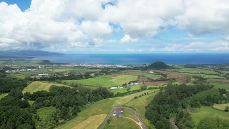 Forward-aerial-of-green-fields,-trees-and-ocean-horizon-at-the-Azores