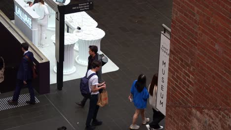 Statische-Aufnahme-Des-Schilds-Des-Shot-Tower-Museums-Der-Coop-In-Melbourne-Central-Mit-Pendlern-Und-Einkaufslustigen,-Die-Durch-Die-Szene-Laufen