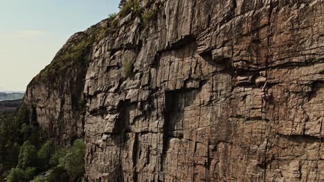 Girl-climbing-rocky-cliff-in-Norway,-extreme-sports,-aerial-view