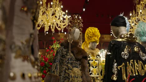 Dolce-And-Gabbana-Luxurious-and-ornate-costumes-on-mannequins-showcased-in-a-red-walled-exhibition-room,-exuding-a-sense-of-opulence-and-artistic-flair