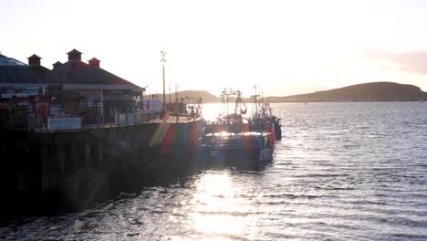 Bright-shimmering-sunlight-over-waterfront-harbour,-boat-and-ocean-water-in-popular-holiday-destination-of-Oban-in-Scotland-UK