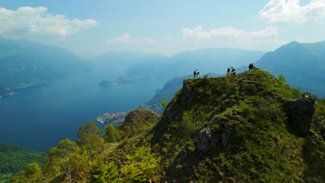 Group-of-tourists-standing-on-a-mountain-overlook,-taking-in-the-panoramic-view-of-Lake-Como-and-its-surrounding