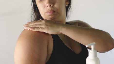 Close-up-of-Hispanic-adult-woman-applies-moisturizer-on-reddened-skin-of-sunburned-shoulder